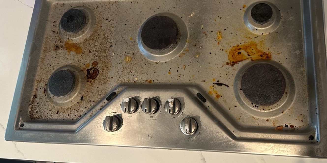 The same cooktop before cleaning, covered in burnt-on grease